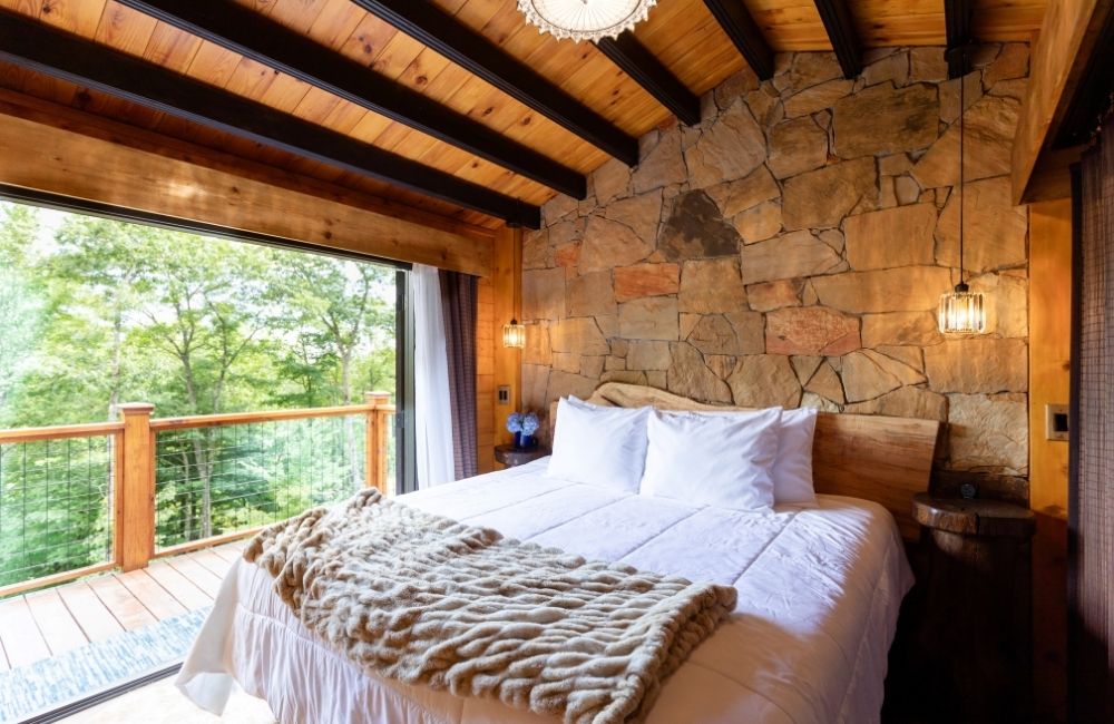 Meraki Escape Brevard NC interior of bedroom with stone wall high ceilings private balcony